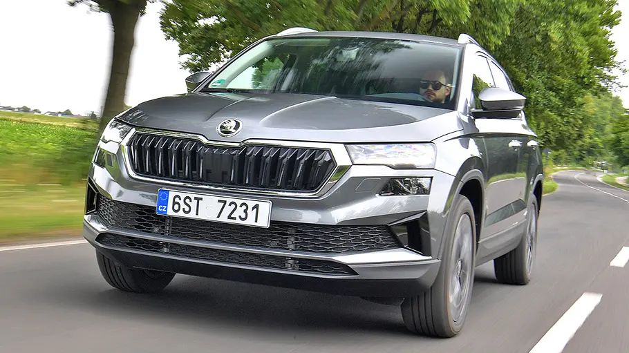 Der Skoda Karoq fährt auf einer Landstraße, von vorne links fotografiert.