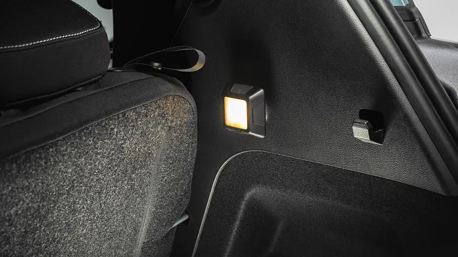 Eine kleine Leuchte strahlt an der schwarzen Seitenverkleidung des Kofferraums im Dacia Spring neben der Rücksitzlehne.