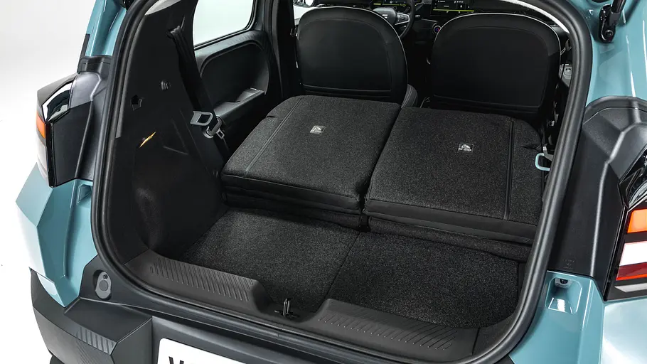 Die geöffnete Heckklappe des Dacia Spring gibt den Blick auf den leeren Kofferraum mit umgeklappten Rücksitzen frei.