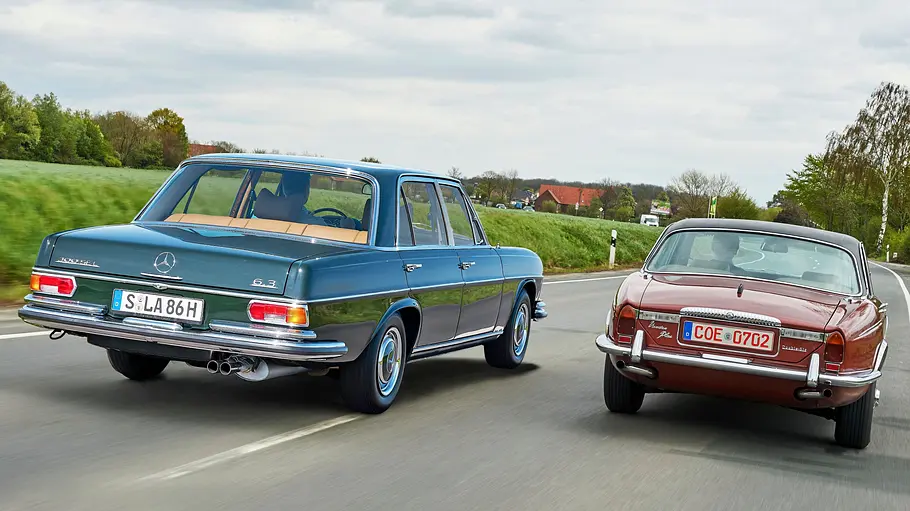 Mercedes 300 SEL 6.3/Daimler Double Six Vanden Plas fahrend von schräg hinten fotografiert. 