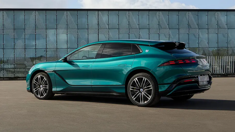 Der Denza Z9 GT statisch von schräg hinten links vor einem verglasten Gebäude.