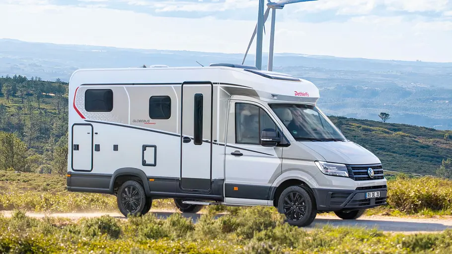 Der Dethleffs Globebus Performance T16 statisch von schräg vorne rechts. Im Hintergrund sind Windkrafträder zu sehen.