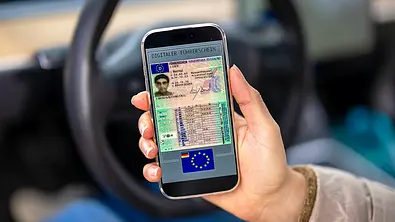 Detailaufnahme von einer Hand, die ein Smartphone hält, auf dem ein Führerschein abgebildet ist. - Foto: Imago