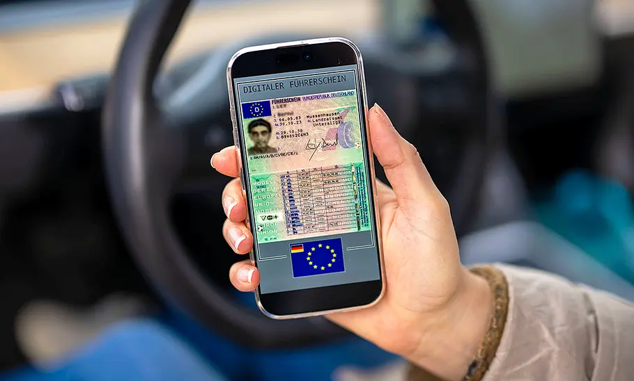 Detailaufnahme von einer Hand, die ein Smartphone hält, auf dem ein Führerschein abgebildet ist.