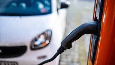 Ein Ladekabel eines E-Autos und im Hintergrund sieht man einen Smart, parkend. - Foto: Imago Ein Ladekabel eines E-Autos und im Hintergrund sieht man einen Smart, parkend. - Foto: Imago