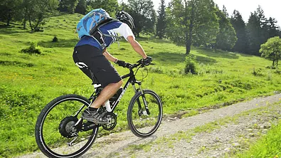 Eine radelnde Person auf einem E-Bike von schräg hinten fotografiert. - Foto: Imago
