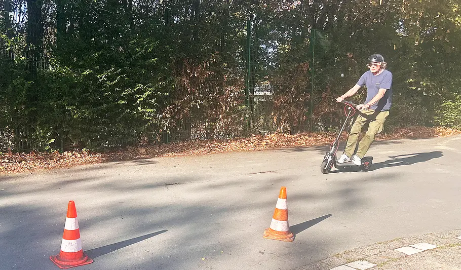 E-Scooter Segway Ninebot F3 Pro D Die Außenaufnahme zeigt einen Testredakteur, der auf dem E-Scooter Segway Ninebot F3 Pro D einen Hütchen-Parcours anfährt.