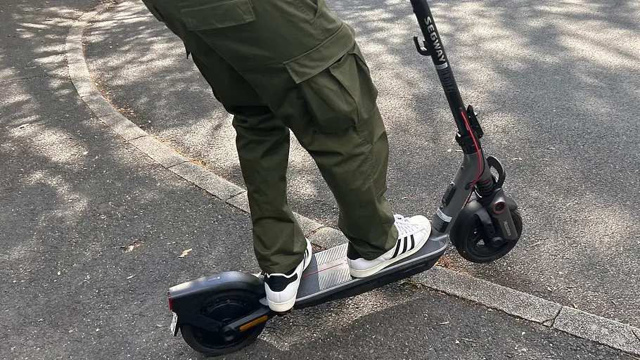 E-Scooter Segway Ninebot F3 Pro D Die Außenaufnahme zeigt einen Testredakteur auf dem E-Scooter Segway Ninebot F3 Pro D beim Überwinden einer Borsteinkante.