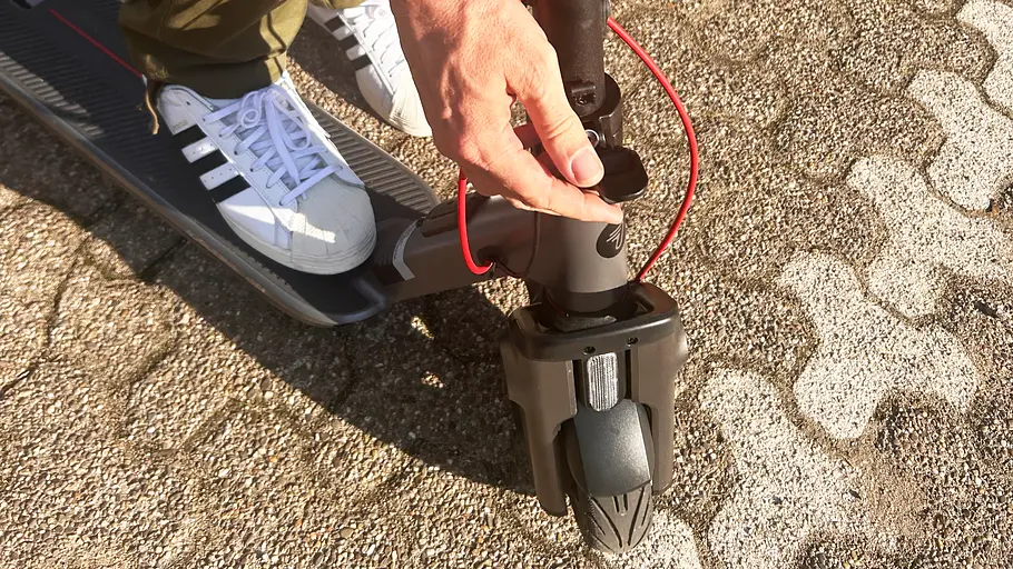 E-Scooter Segway Ninebot F3 Pro D Die Detailaufnahme zeigt die Hand eines Testredakteurs beim Entriegeln des Klappmechanismus des Segway Ninebot F3 Pro D.