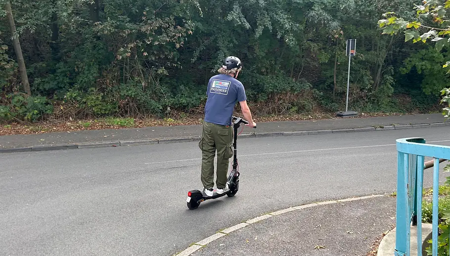 E-Scooter Segway Ninebot F3 Pro D Die Außenaufnahme zeigt einen Testredakteur auf dem E-Scooter Segway Ninebot F3 Pro D von hinten beim Bergabfahren.