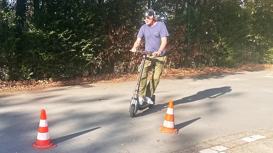 E-Scooter Segway Ninebot F3 Pro D Die Außenaufnahme zeigt einen Testredakteur auf dem E-Scooter Segway Ninebot F3 Pro D beim Durchfahren eines Hütchen-Pacours.