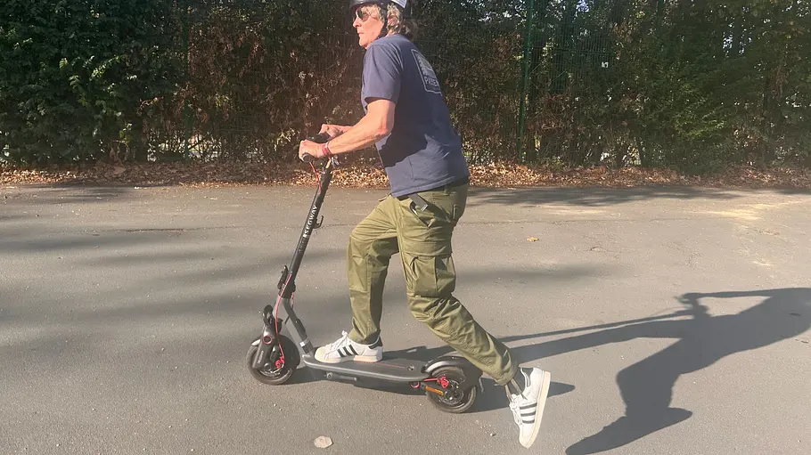 E-Scooter Segway Ninebot F3 Pro D Die Außenaufnahme zeigt einen Testredakteur auf dem E-Scooter Segway Ninebot F3 Pro D beim Anfahren (Skaten mit dem linken Fuß).