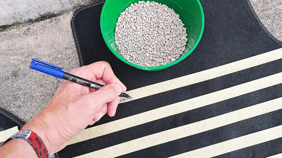 Ein Tester beschriftet von Hand eine in Segmente eingeteilte Auto-Fußmatte.