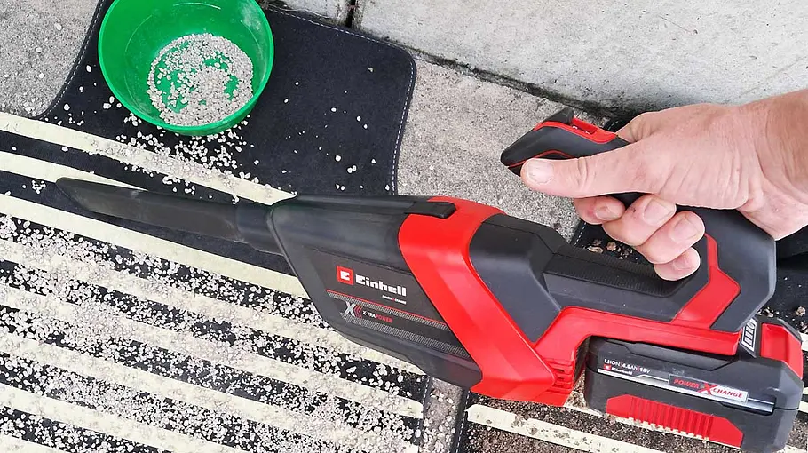 Der Akku-Handstaubsauger Einhell TE-HV 18/06 Li – Soloin der Hand eines Testers beim Absaugen einer präparierten Fußmatte.