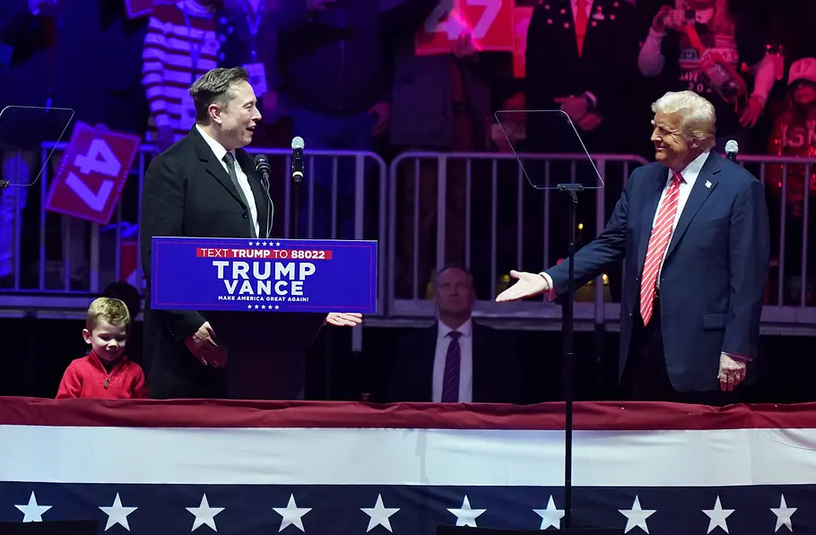 Elon Musk und Donald Trump während einer Veranstaltung. Im Hintergrund sieht man viele Menschen.
