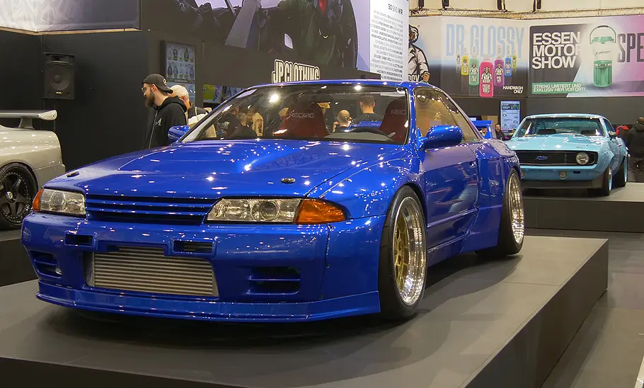 JP Performance auf der Essen Motor Show 2025 Mehrere Fahrzeuge stehen auf einem Podest auf einem Messestand.