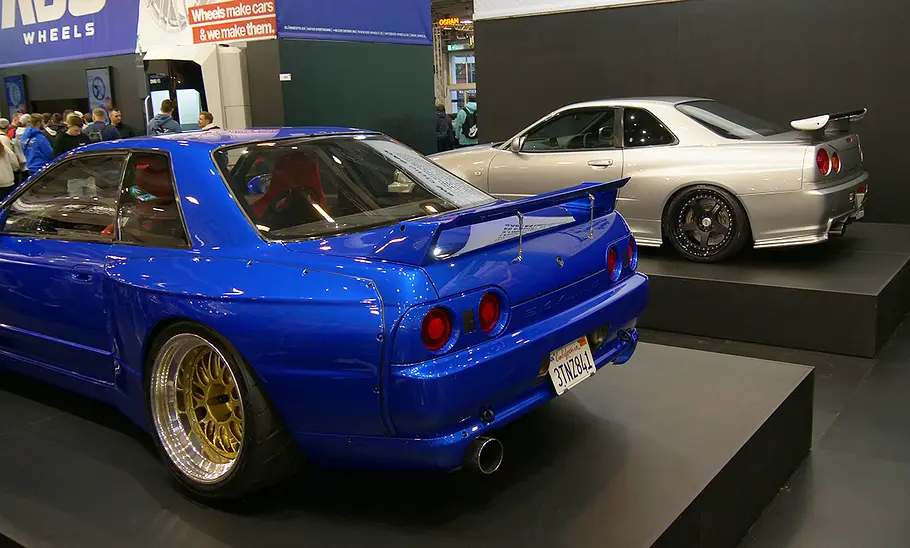 JP Performance auf der Essen Motor Show 2025 Das Heck von je zwei Fahrzeugen, die auf einem Podest stehen.