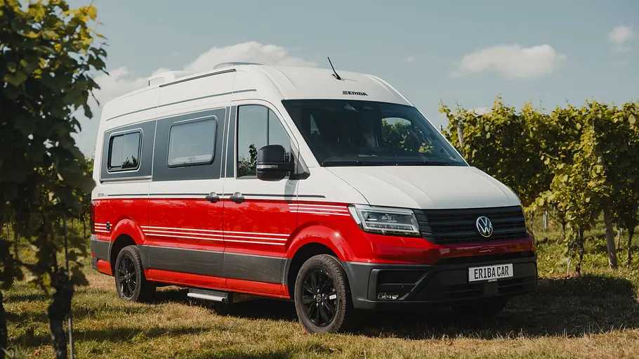 Der Eriba Car statisch von schräg vorne rechts vor Weinreben auf einer Wiese parkend.