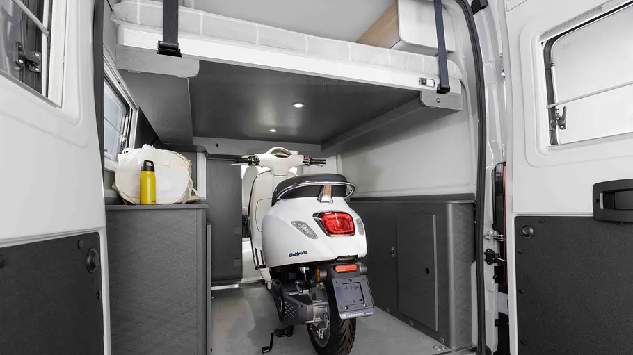 Etrusco CV 640 PB+ Blick durch die geöffneten Hecktüren in die Heckgarage des Etrusco CV 640 PB+, in der ein Motorroller unter dem hochgefahrenen Hubbett steht.