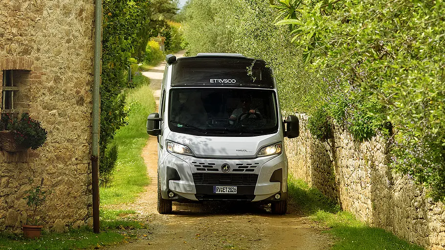 Etrusco CV 640 PB+ Der Etrusco CV 640 PB+ statisch von vorne auf einer engen Schotterstraße zwischen einer Wand und einem Haus.