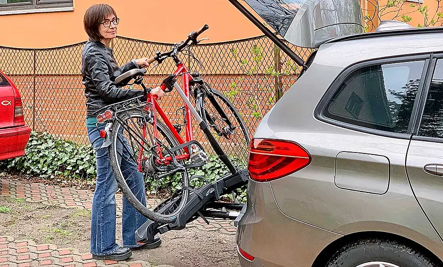 Fahrradträger-Test: Thule Epos 2 Fahrradträger Thule Epos 2 am Testwagen mit einem Fahrrad, seitlich fotografiert mit Testperson beim Abklappen des Trägers.