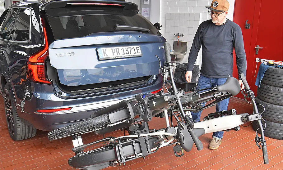 Eufab Premium Go+ abgeklappt mit zwei Fahrrädern, hinter Volvo XC90 mit sich öffnender Heckklappe, fotografiert von hinten.