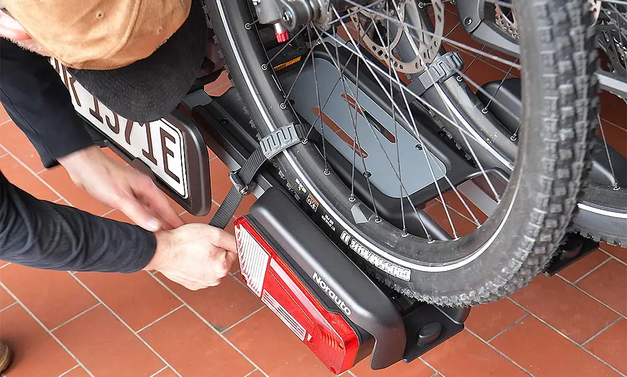 Tester beim Verzurren eines Rades am Norauto E-Fit 300-2 mit verrutschendem Felgenschutz, fotografiert von oben.