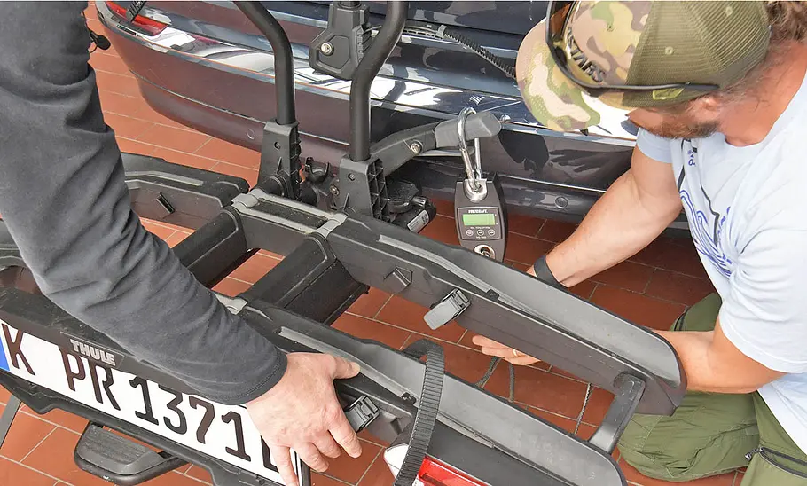 Das Foto zeigt zwei Tester bei der Montage des Thule Fahrradträger Easyfold 3 an die Anhängerkupplung des Testwagens.