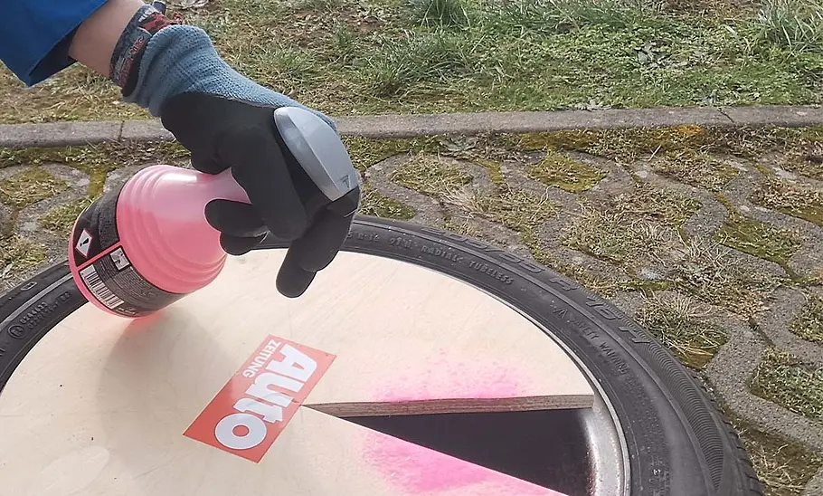 Felgenreiniger von Dr. Wack wird mithilfe einer Holzschablone auf die Außenseite einer Testfelge gesprüht.