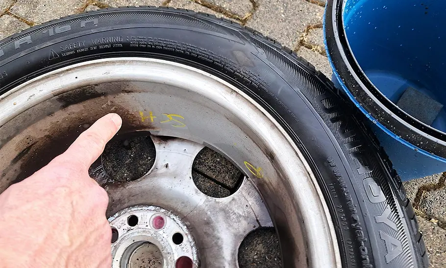 Der Finger eines Testredakteurs, der die Reinigungsleistung begutachtet, zeigt auf eine Testfelge.