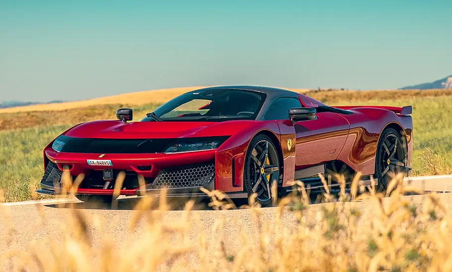 Der Ferrari F80 (2025) steht auf einer Landstraße zwischen Kornfeldern, fotografiert von vorne links.