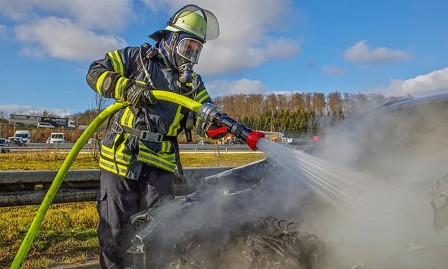 Ein Feuerwehrmann beim Löschen eines brennenden Autos.