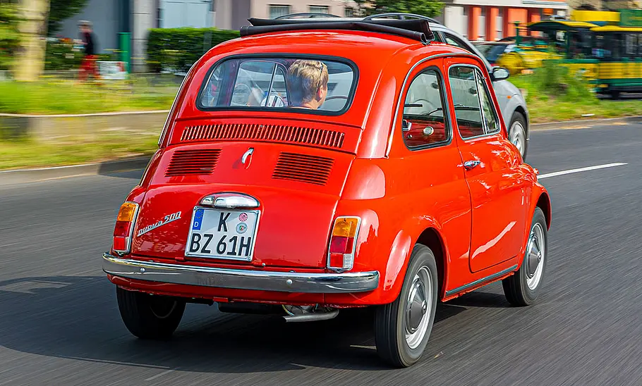 Der Fiat 500 fahrend von schräg hinten fotografiert.