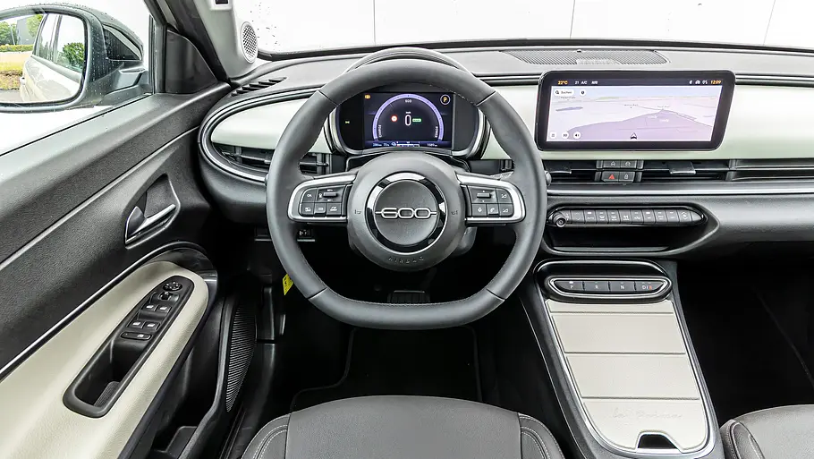Cockpit des Fiat 600e mit rundem Kombiinstrument, Touchscreen und heller Mittelkonsole
