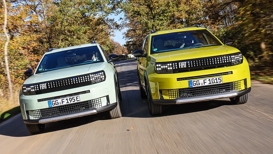 Fiat Grand Panda Elektro und Hybrid fahren nebeneinander auf einer Landstraße,. von vorne fotografiert.