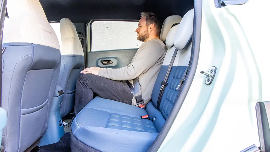 Ein Mann sitzt im Fond des Fiat Grande Panda Elektro.