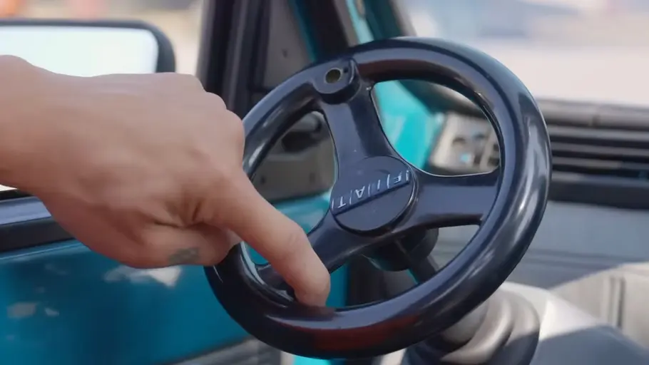 Lenkrad des Fiat Panda for One mit Hand, fotografiert von hinten.