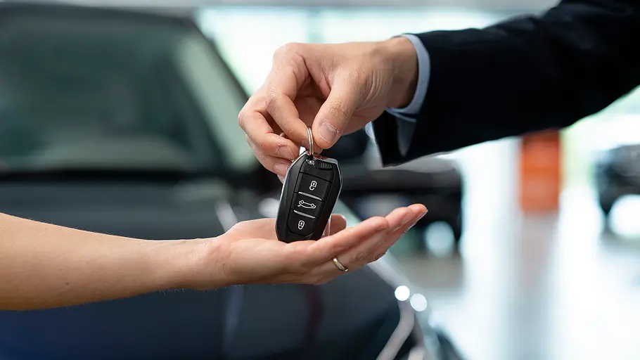 Firmenwagen Fallstricke Ein Autoschlüssel wird von einer Hand zur nächsten Hand übergeben.