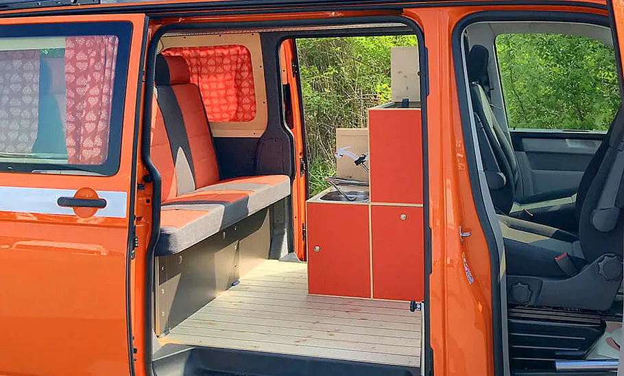 Flowcamper Frieda Das Bild zeigt den Wohnraum des Flowcamper Frieda von der Seite durch die geöffnete Schiebetüre fotografiert.