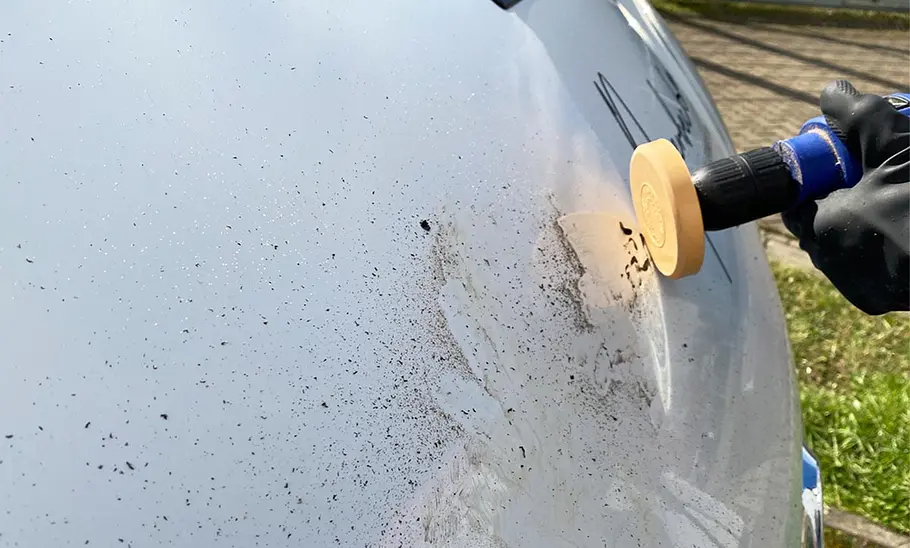 Ein Folienradierer an einer Bohrmaschine beim Ablösen einer Autobeschriftung.