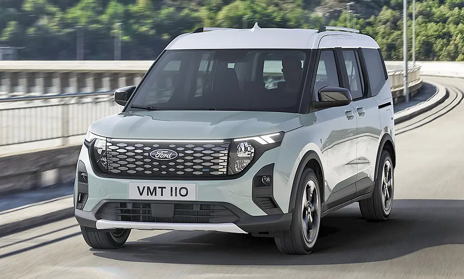 Der Ford E-Tourneo Courier (2025) fährt auf einer Straße, von vorne links fotografiert.
