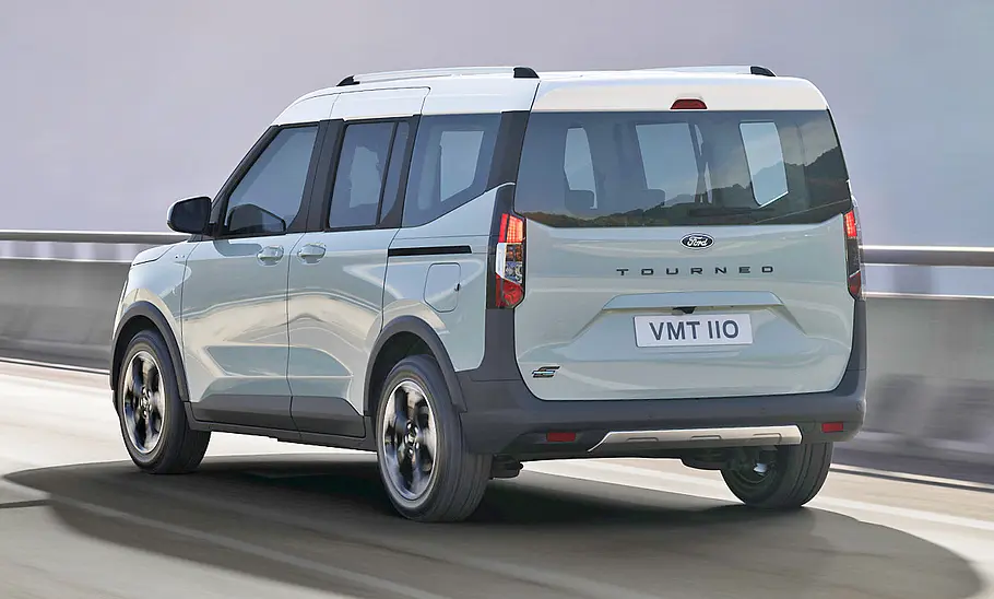 Der Ford E-Tourneo Courier (2025) fährt auf einer Straße, von hinten links fotografiert.