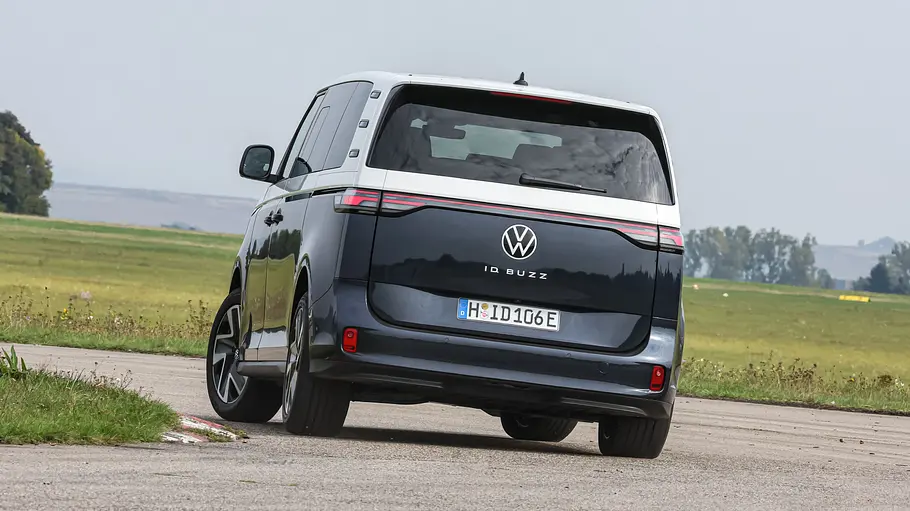 Der VW ID. Buzz LWB fährt durch eine Linkskurve, von hinten fotografiert.