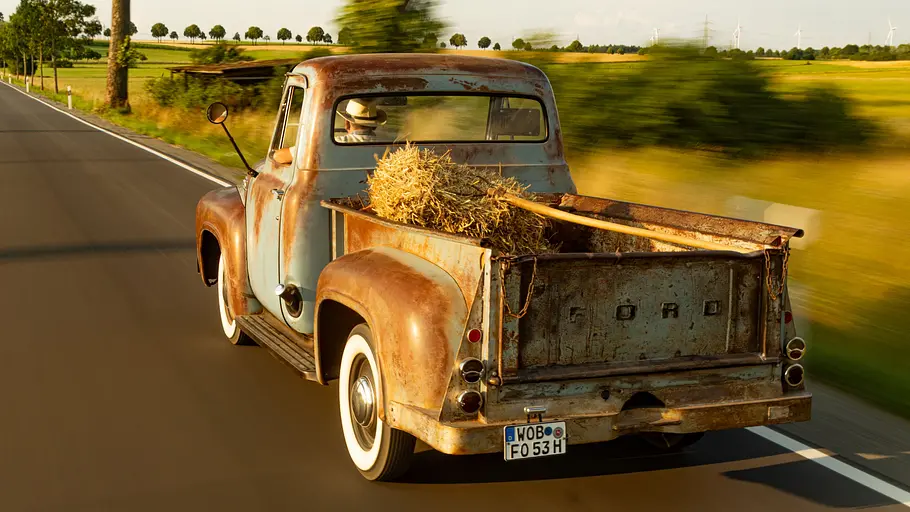 Ford F-100 V8 Stepside Der Ford F-100 V8 Stepside fahrend von schräg hinten