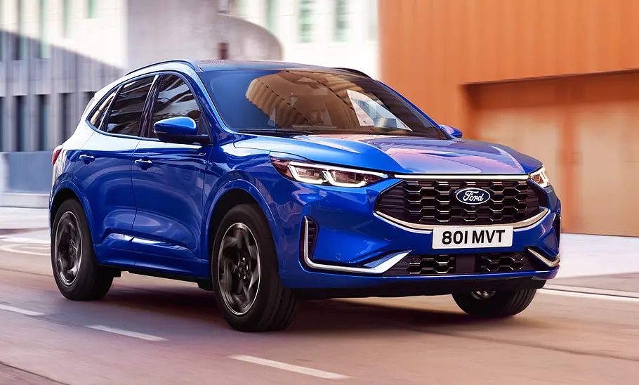 Das Ford Kuga Facelift (2024) fährt durch eine Stadt, von vorne rechts fotografiert.