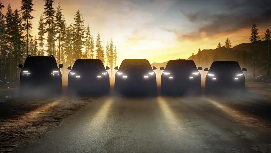 Neue Ford-Modelle Fünf Autos stehen im Halbdunkeln nebeneinander auf einer Waldlichtung, man erkennt nur Silhouetten und Lichtsignaturen.