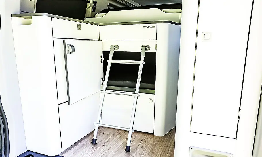 Ford Nugget (2024) Die Innenaufnahme zeigt die komplett zum Bett umgebaute Rückbank im Ford Nugget (2024).