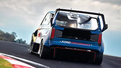 Blick von hinten auf den fahrenden Ford Transit SuperVan 4.2, der auf einer Rennstrecke entlang fährt. - Foto: Ford
