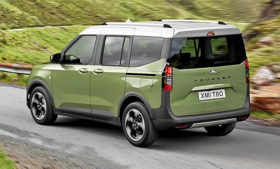 Der Ford Tourneo Courier (2024) fährt auf einer Straße, von hinten links fotografiert.