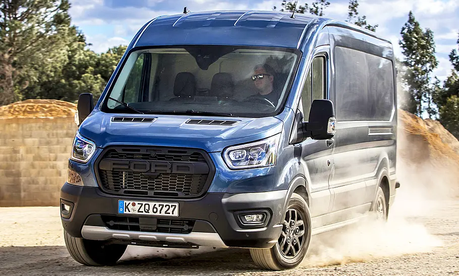 Der Ford Transit Trail (2020) fährt durchs lose Gelände, von vorne links fotografiert.